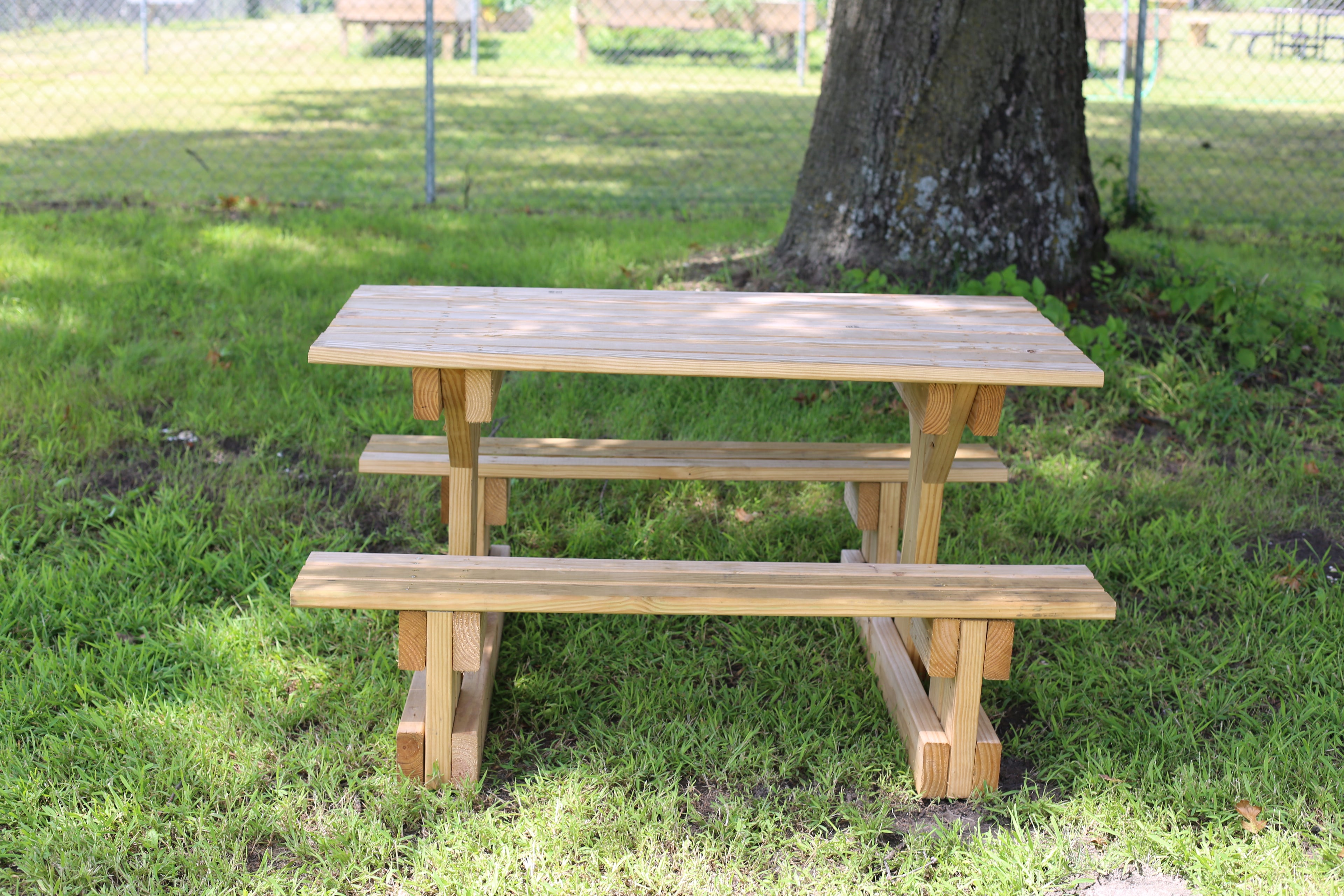Wooden picnic table with benches in a park setting